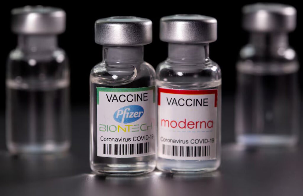 covid-19 vaccine bottle with syringe placed beside it on a clinical table