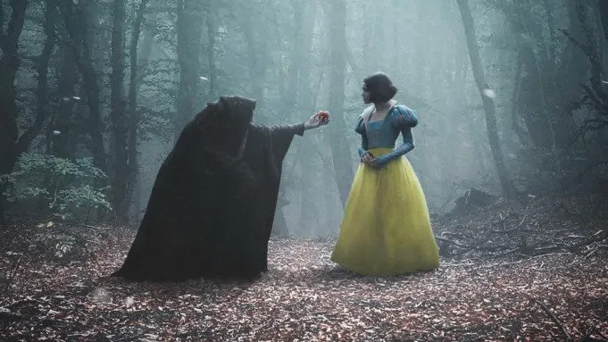 gal gadot as the evil queen offering the poisoned apple to snow white