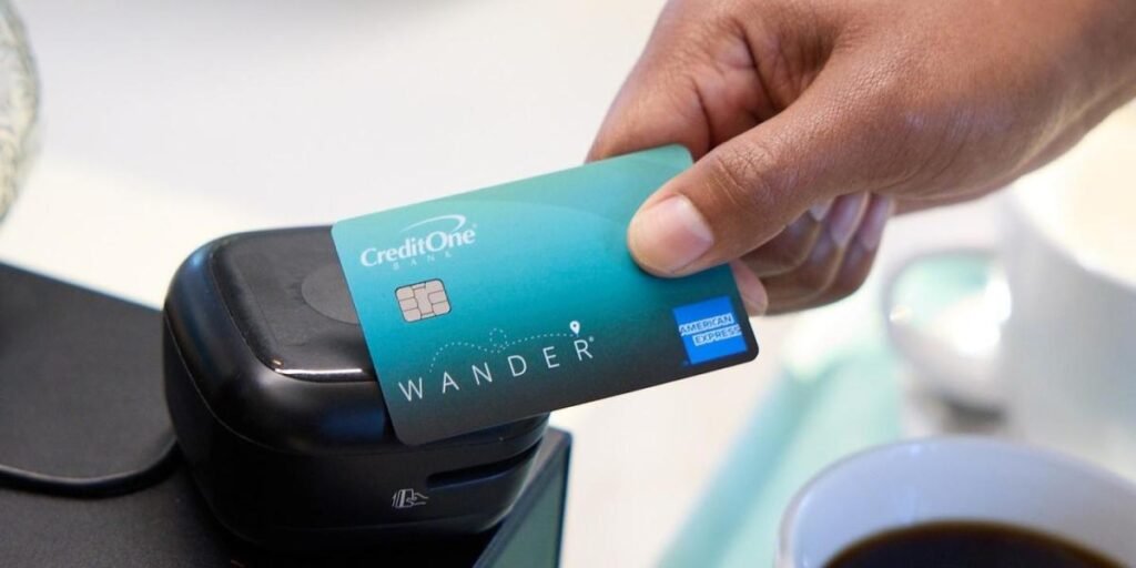 hand holding a credit one credit card over a payment terminal