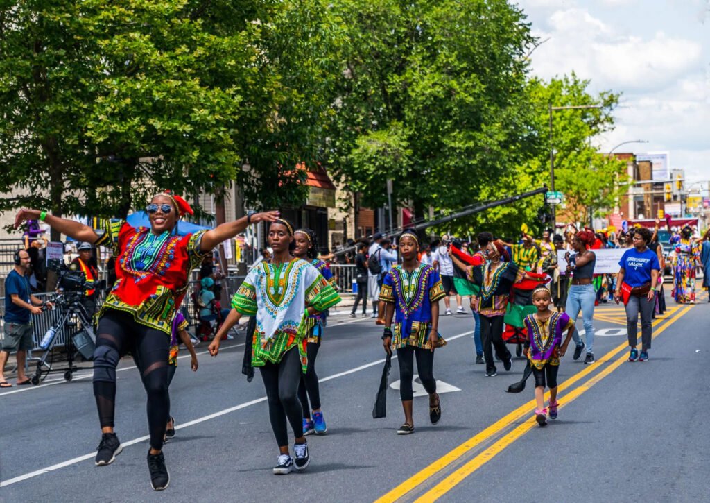 juneteenth parade with dancers and juneteenth flag on a busy city street